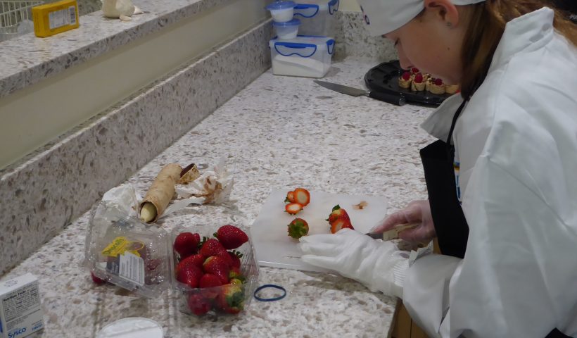 Child cuts up a strawberry